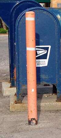 rusty bollard in front of mailbox